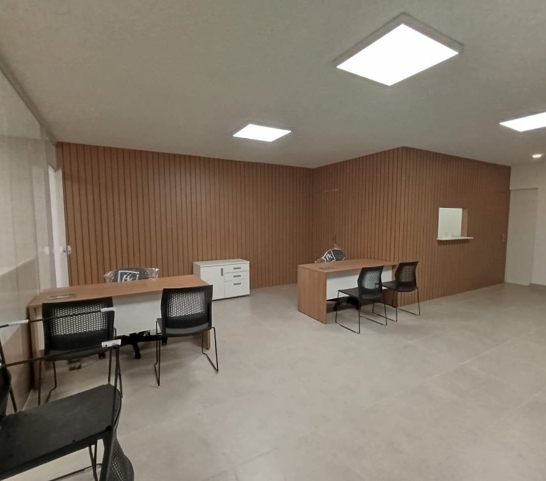 Sala de trabalho com painel ripado em madeira e duas bancadas