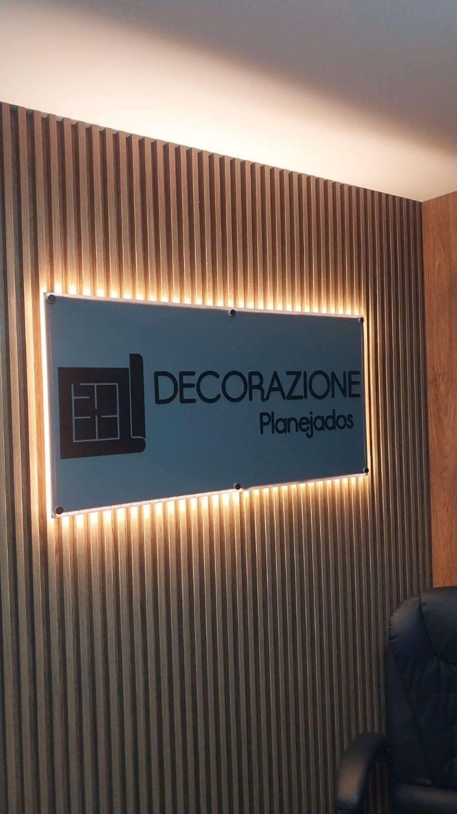 Placa iluminada da Decorazione Planejados sobre painel ripado em madeira