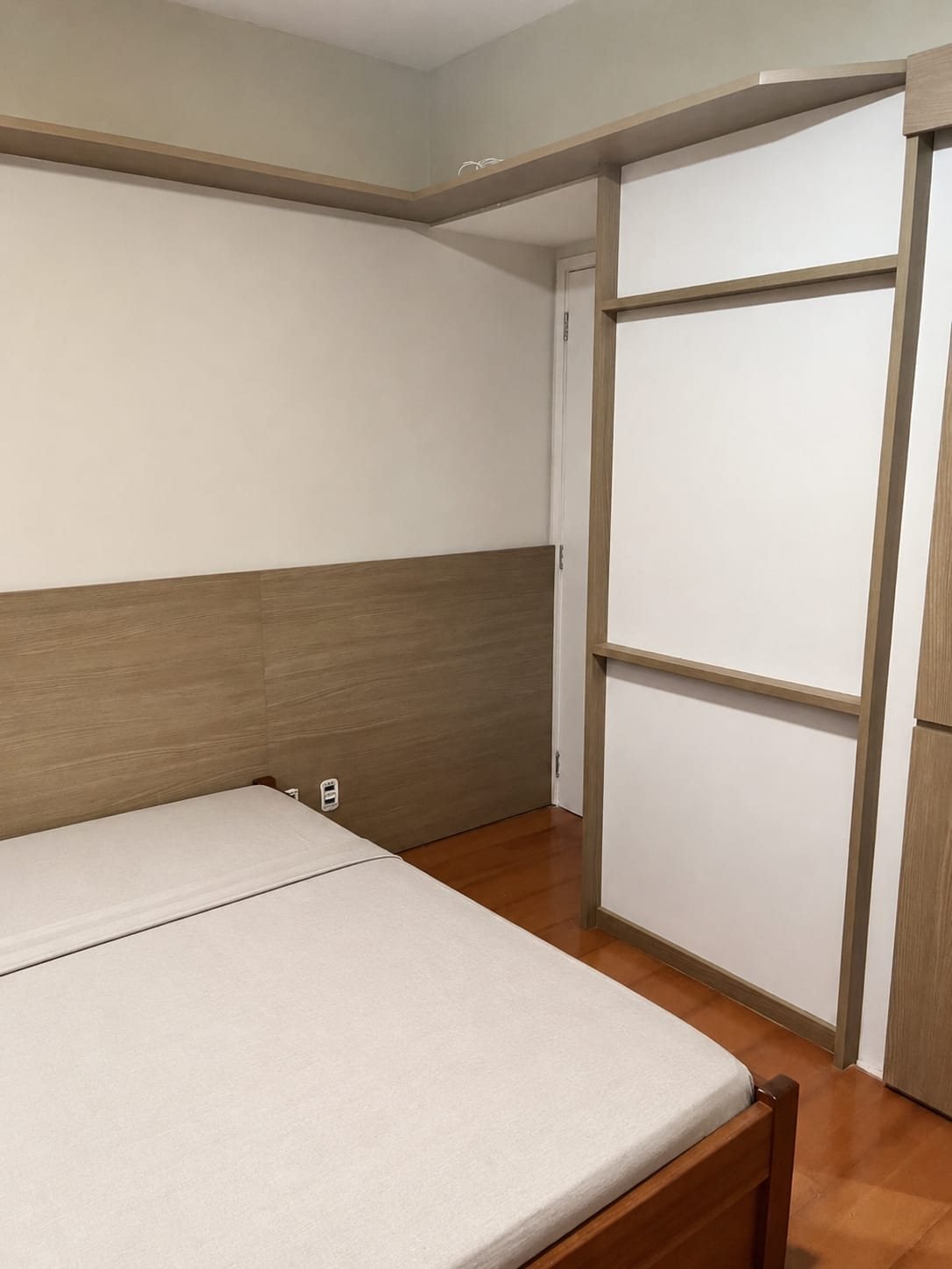 Quarto com cabeceira em madeira e prateleira alta
